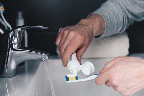 Man Putting Toothpaste on a Toothbrush