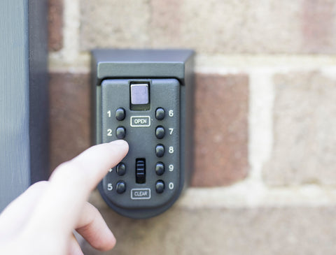 A Hand Fingers Entering a Code on a Lock Box